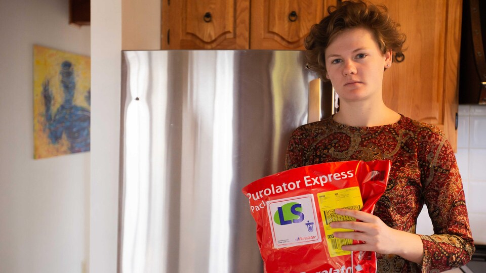 Une femme tient une enveloppe de Purolator dans ses mains.