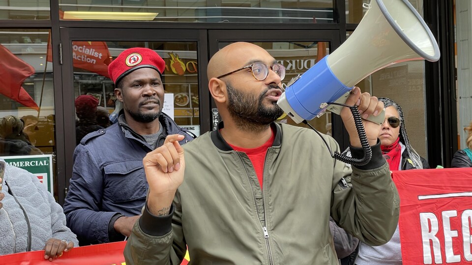 Syed Hussan brandit un porte-voix lors d'une manifestation à Toronto.