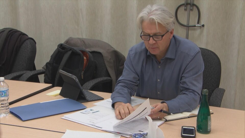 Un homme assis à une table avec des documents devant lui