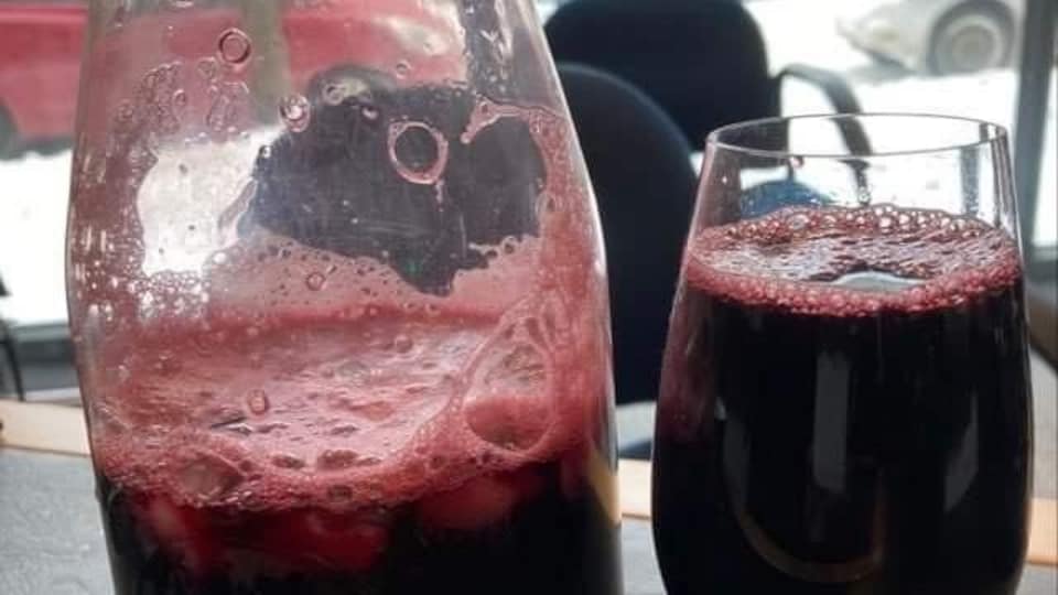 Un carafon et une coupe contenant une boisson de couleur rouge vin.