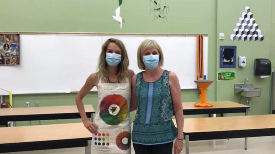 Deux femmes posent ensemble dans une salle de classe d'art.