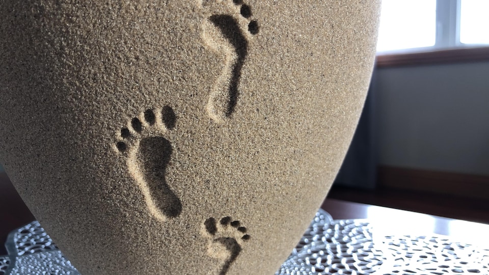 L'urne faite en sable avec des traces de pieds. 