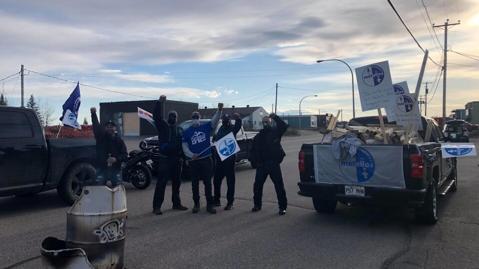 Quatre hommes le poing en l'air et des drapeaux du syndicat à la main.