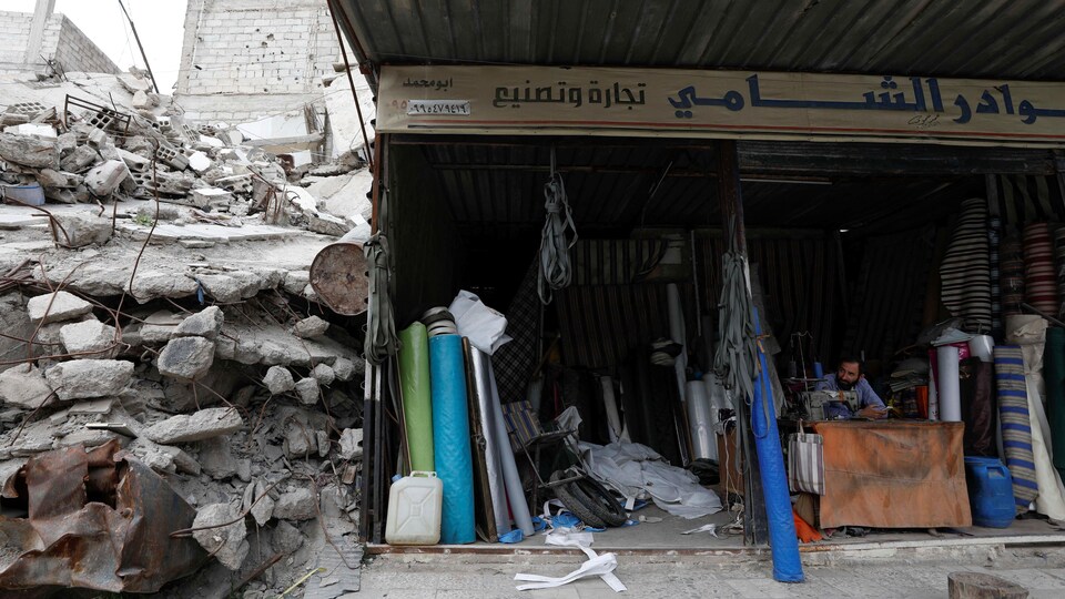 Un magasin de tissu près d'un immeuble détruit.