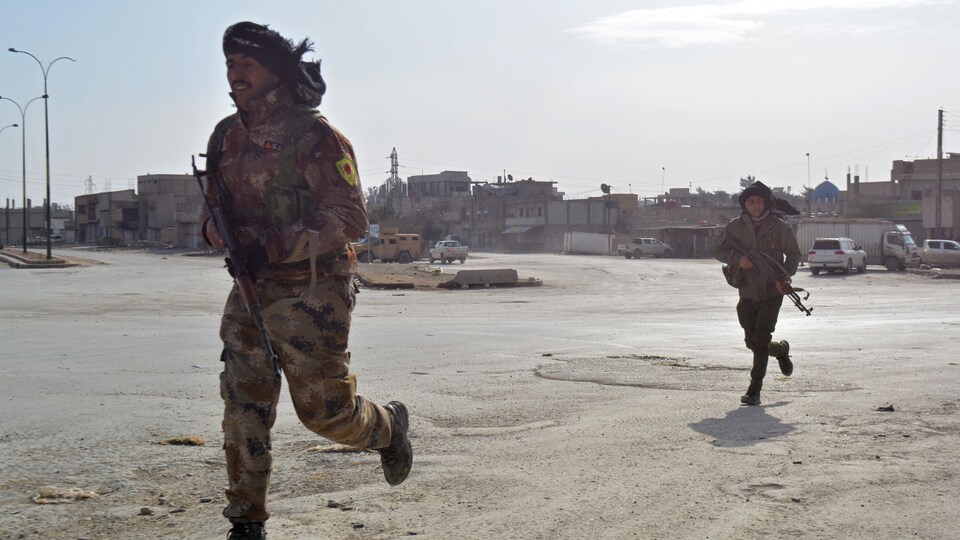 Deux membres des Forces démocratiques syriennes (FDS) traversent une rue à la course à Hassaké, en Syrie, le dimanche 23 janvier 2022.
