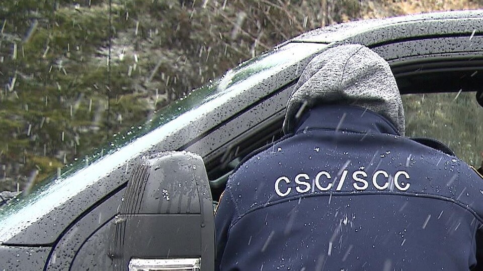 Un employé de Service correctionnel du Canada se tient sur le bord du véhicule de l'employé se rendant au travail.
