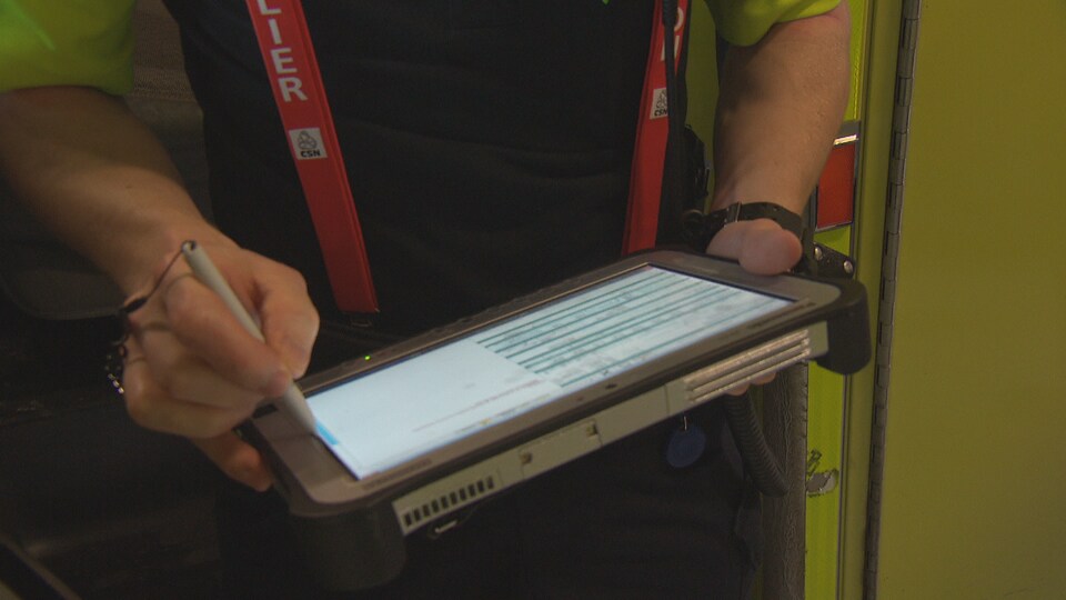Un ambulancier tient une tablette électronique