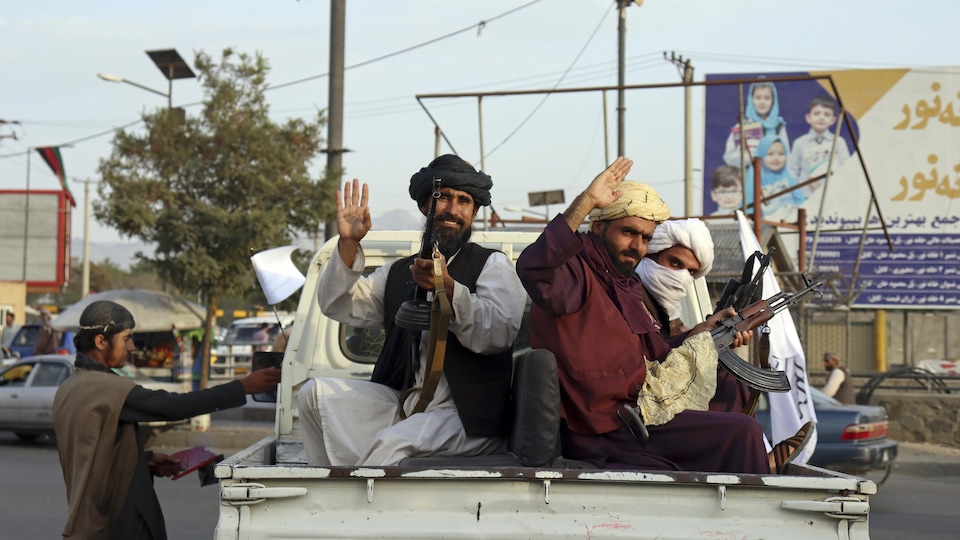Des combattants talibans armés sont assis dans une camionnette de marque Toyota.