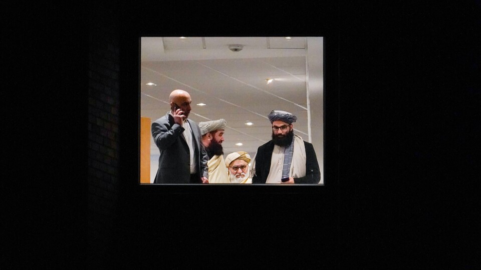 Trois talibans sont près d'un homme qui parle au téléphone.