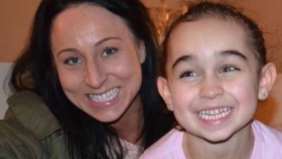 Sara Baillie smiled next to her little girl who was also smiling.