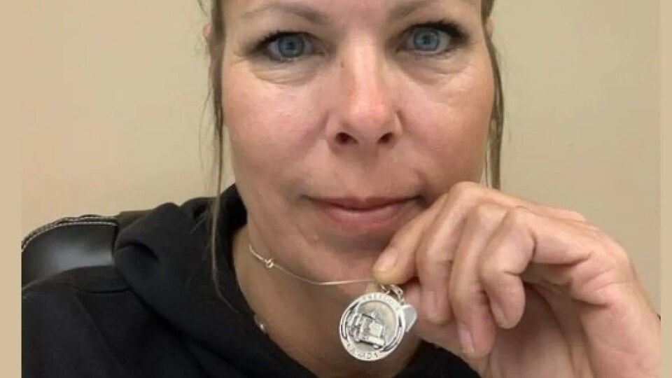 A woman shows a pendant. 