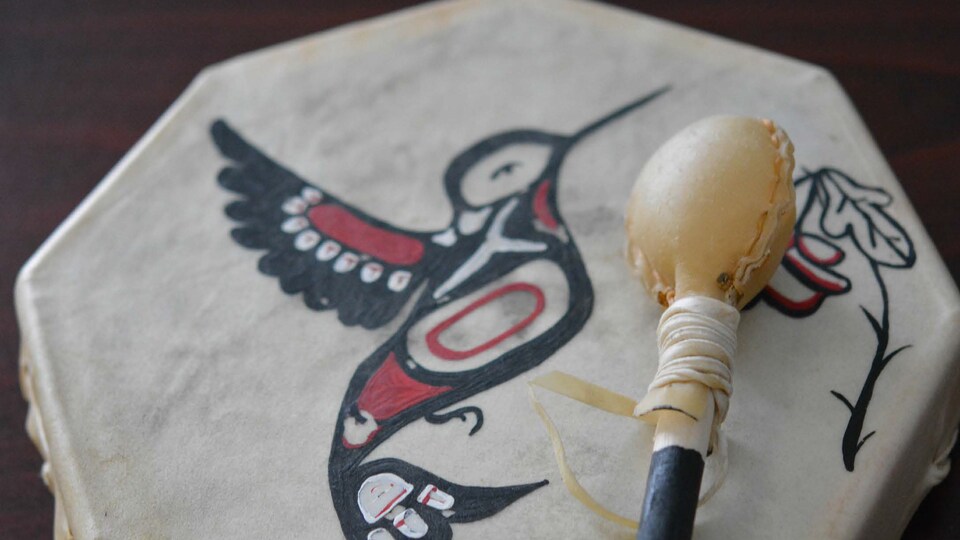 Un tambour autochtone sur lequel un oiseau et une fleur sont dessinés.