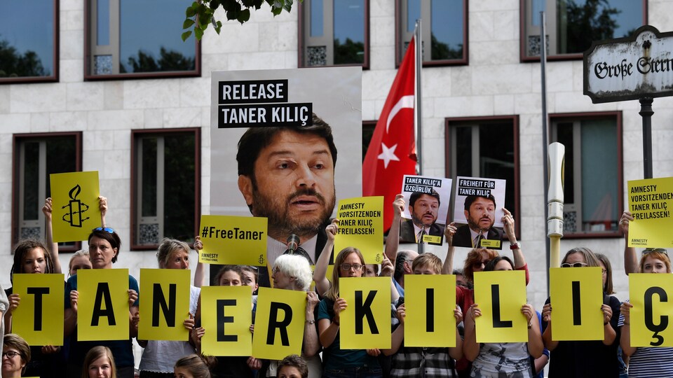 Des activistes tiennent des photos de Taner Kilic ou des lettres formant son nom devant l'ambassade turque, à Berlin.