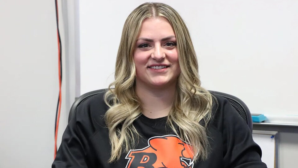 A young blonde woman is wearing a black sweater with the BC Lions logo.