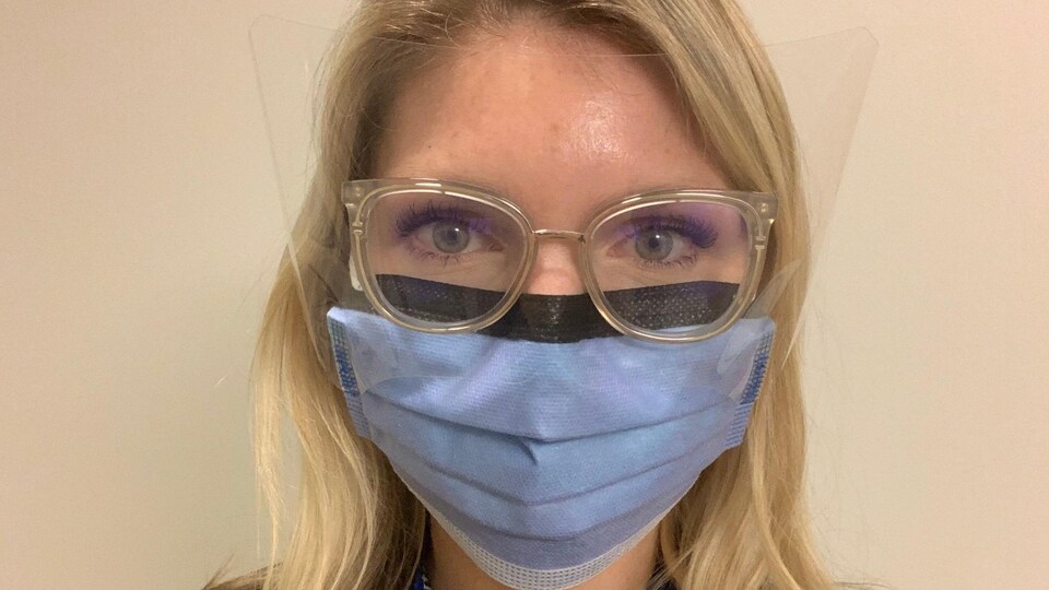 Une infirmière portant un masque et une visière.