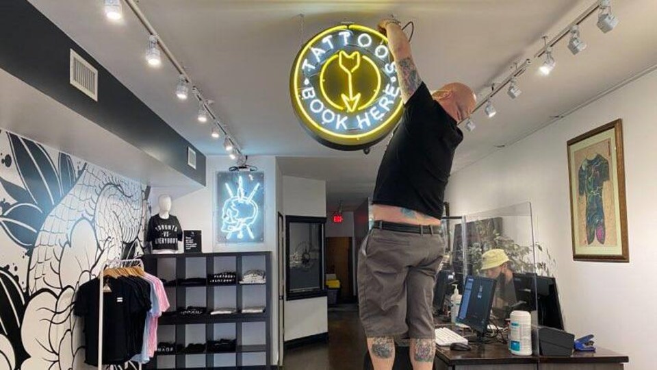 Le directeur d'un salon de tatouage accroche une enseigne dans sa boutique.