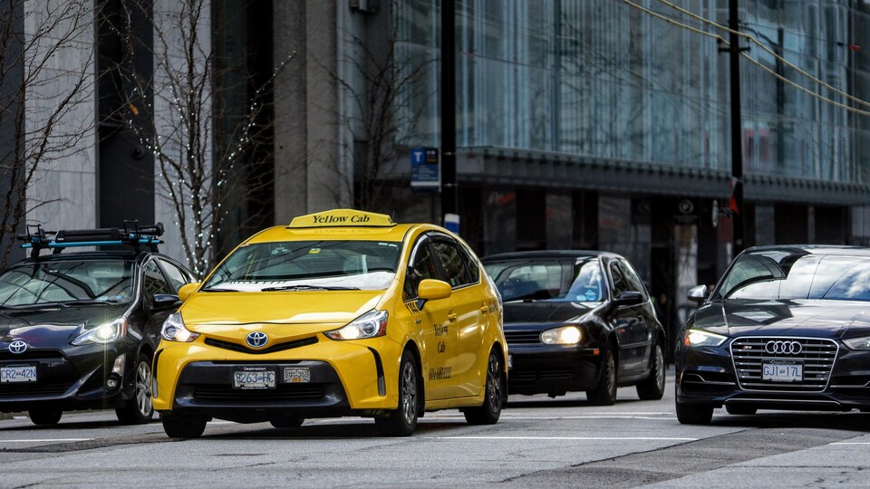 Un taxi jaune est dans une rue, entouré d'autres véhicules.
