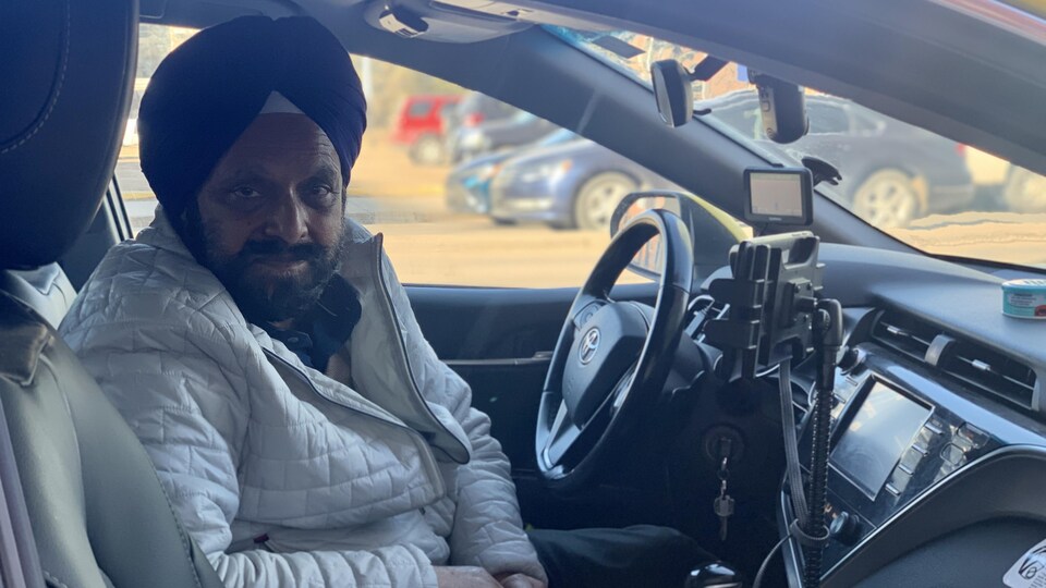 Jagdish Loteuy est assis dans son taxi, stationné dans la rue.