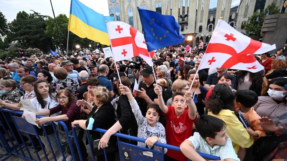 Des enfants agitent des drapeaux géorgiens et européens dans une foule à Tbilissi.