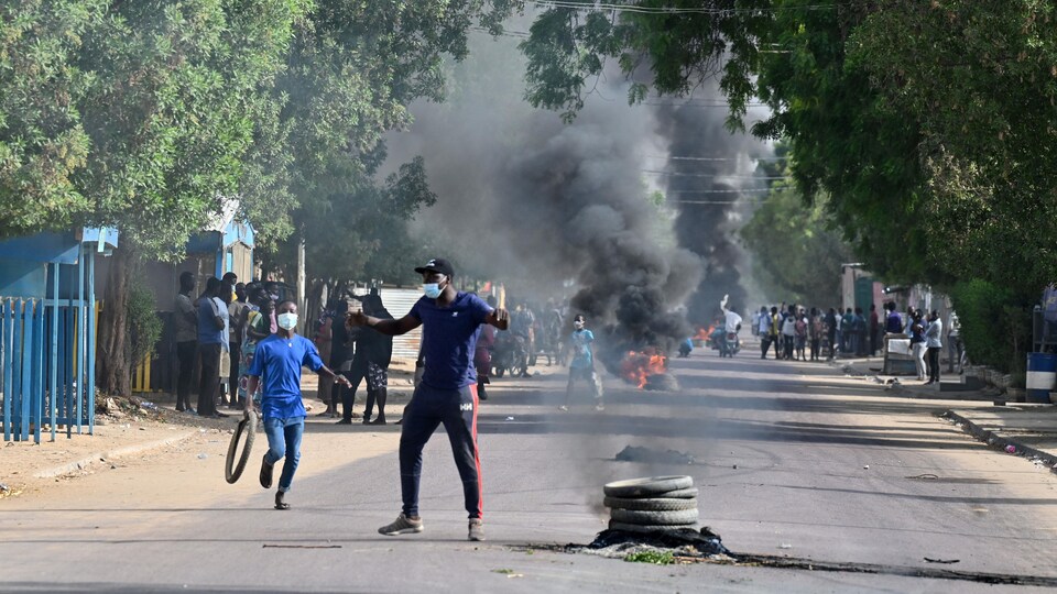 Des manifestants brûlent des pneus au milieu d'une rue.