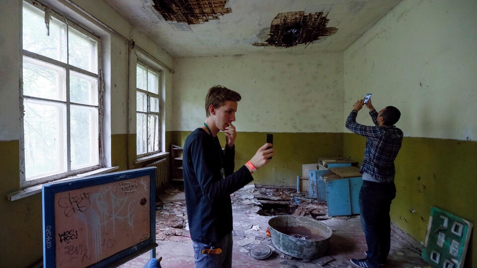 Deux hommes prennent des photos dans une pièce dévastée.
