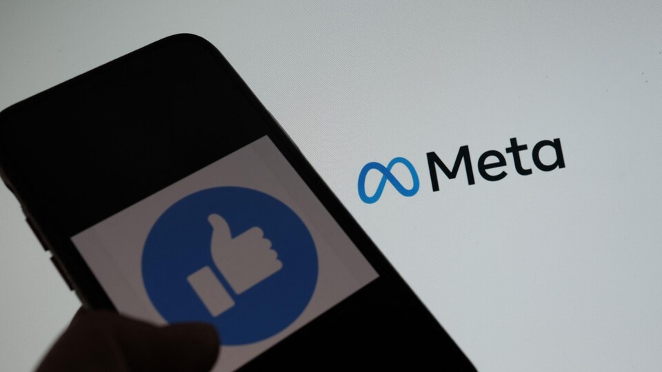 Un téléphone cellulaire avec une image de pouce en l'air devant le logo de Meta.