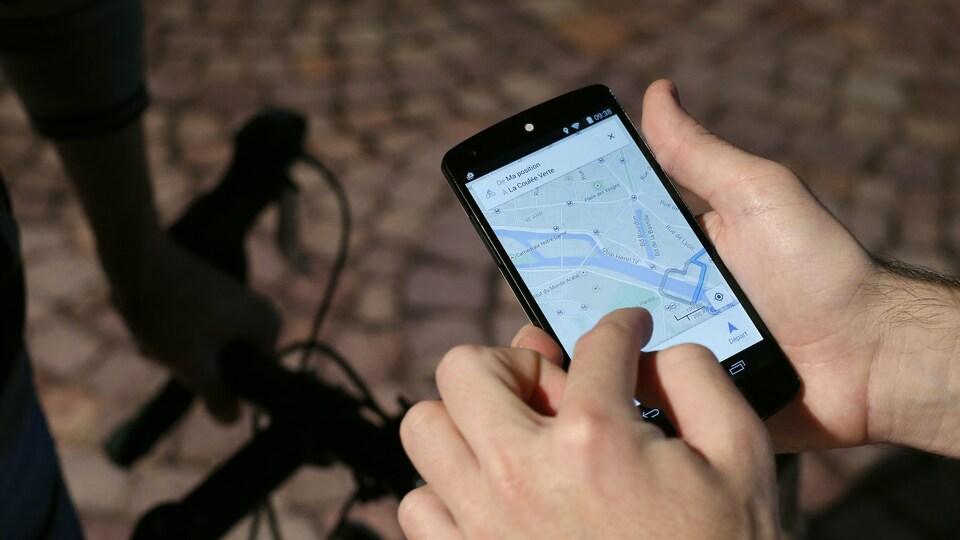 Un homme utilise une application de type GPS sur son téléphone intelligent.