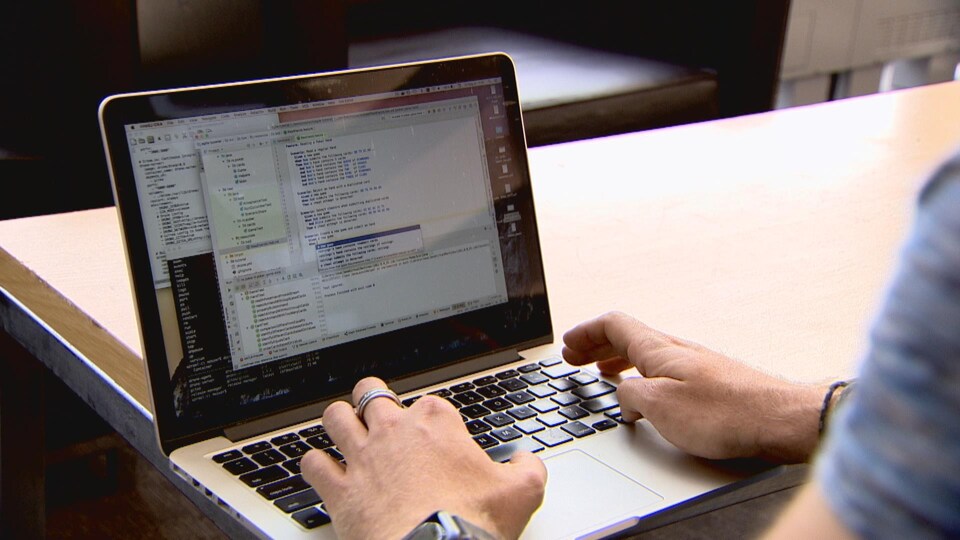 Un ordinateur portable avec des insciptions codées. On voit les mains d'une personne sur le clavier.