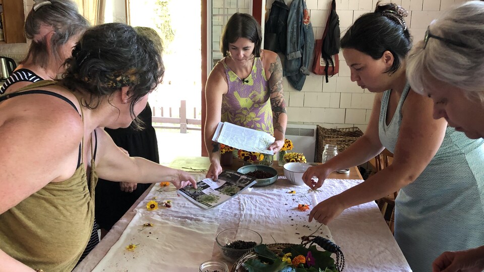 Des femmes sont réunies autour d'une table où se trouvent des fleurs. 