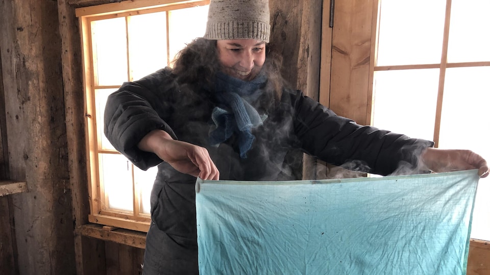 Dans son atelier, Dahlia Milon tient un morceau de tissu de couleur indigo.  