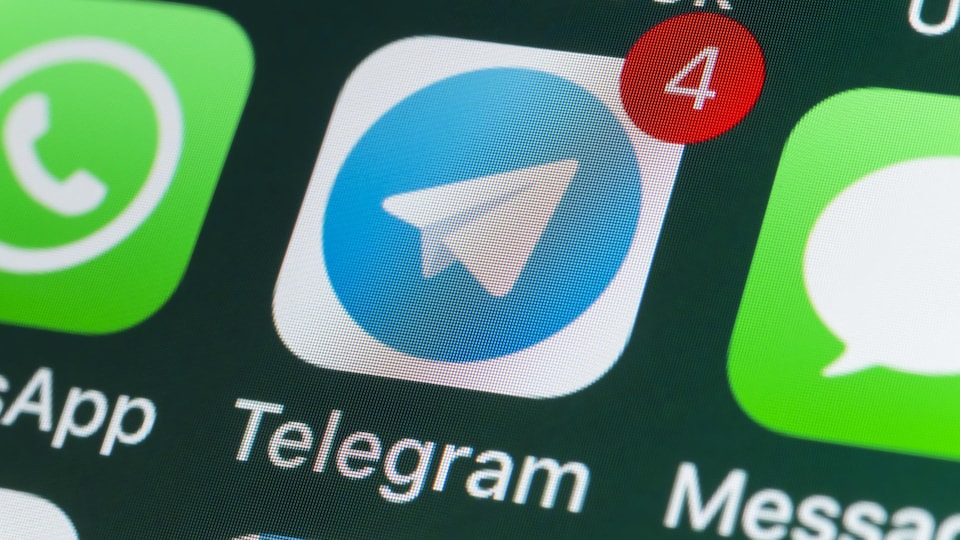 Une photo en gros plan d'un écran de téléphone sur lequel sont affichées les icônes de différentes applications de messagerie, dont celle de Telegram.