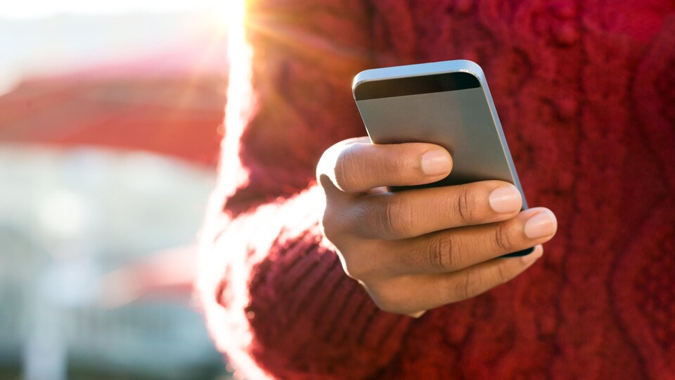 Une femme tient un téléphone intelligent.