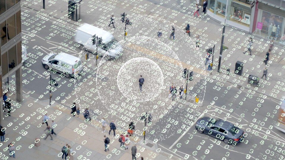Un homme traverse une rue et des ondes émanent de son corps pour représenter des données mobiles.