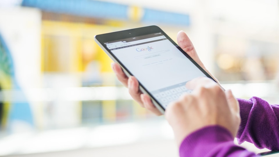 Une personne écrit sur son téléphone portable devant un magasin.
