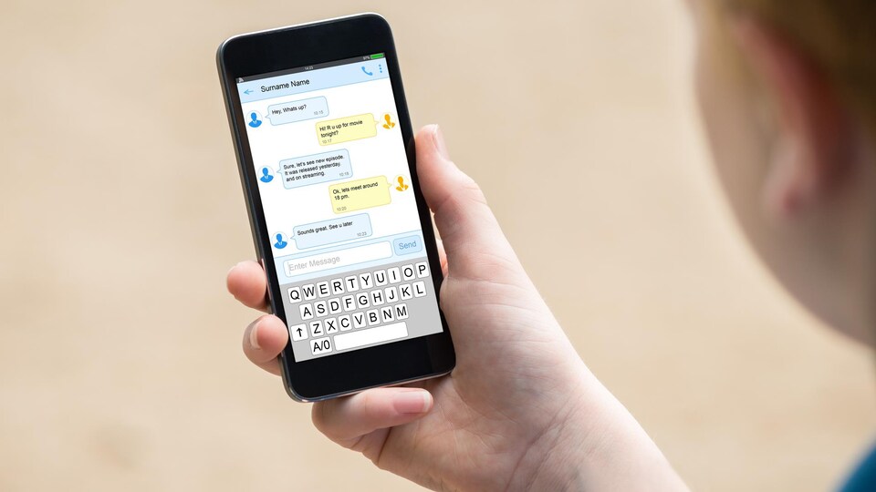 Un jeune homme regarde l'écran de son téléphone.