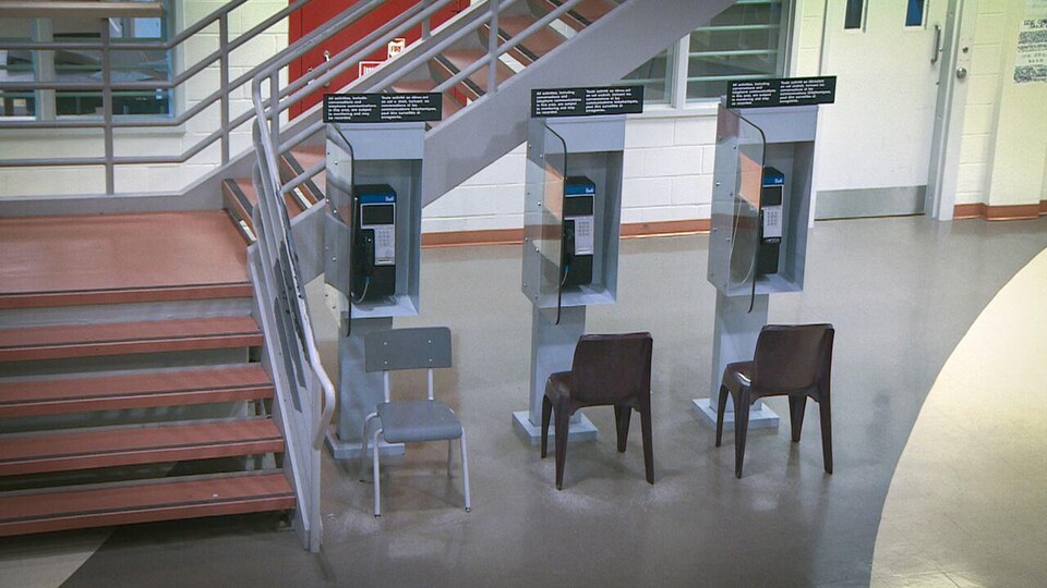 Three public telephones next to each other at the bottom of a staircase in a correctional center.
