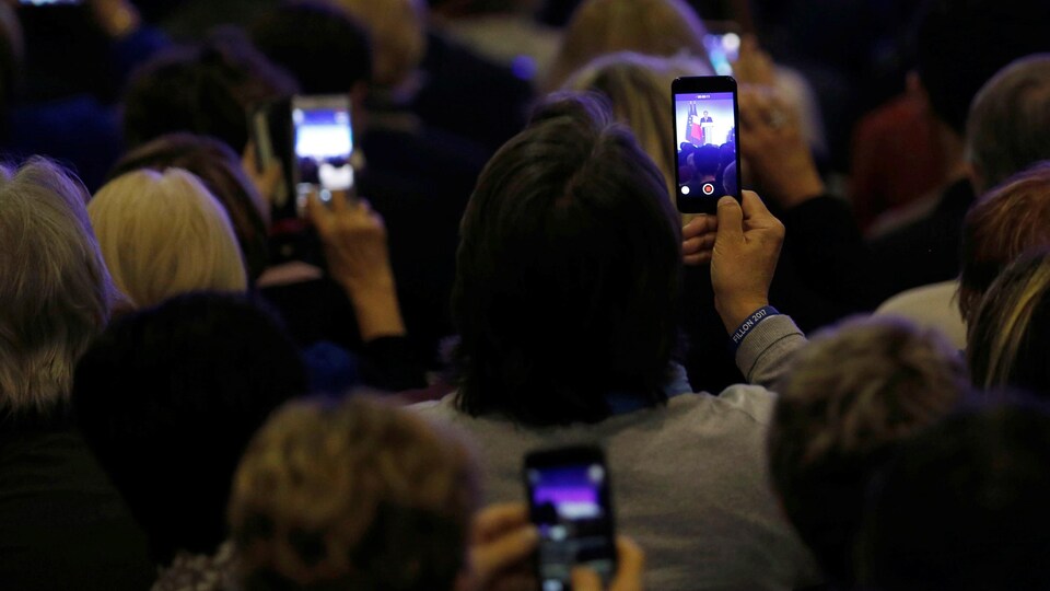 Des participants à un rassemblement du candidat François Fillon en France prennent des images avec leur téléphone.