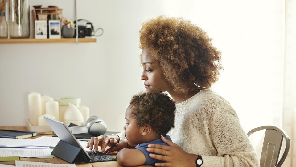 Une mère regardant une tablette avec son enfant sur les genoux.