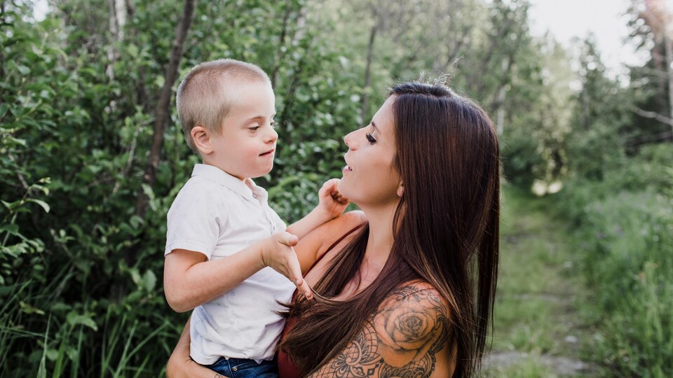 Une mère tient dans ses bras son fils atteint de la trisomie 21.