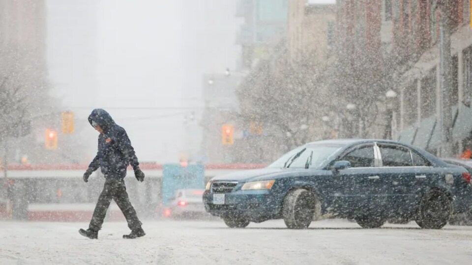 Un homme marche sous la neige.