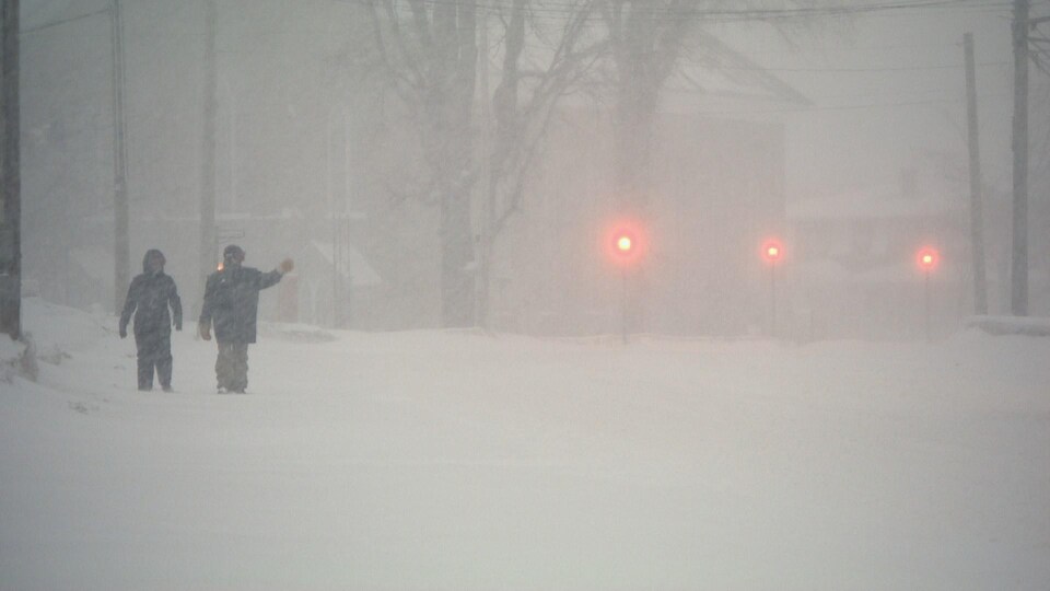 Deux personnes marchent dans la tempête. 