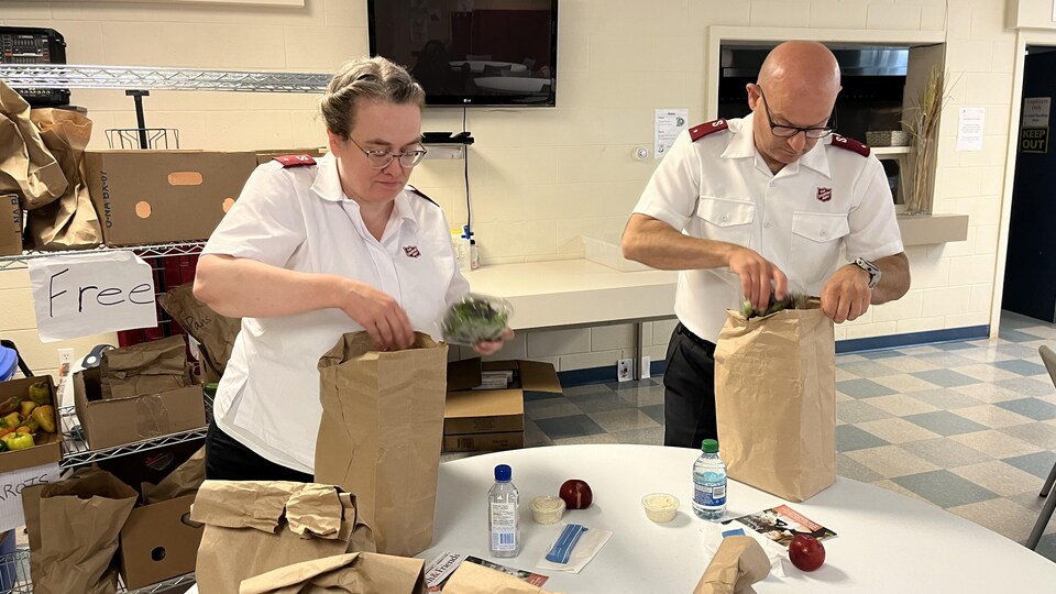 Deux personnes remplissent des sacs à lunch.