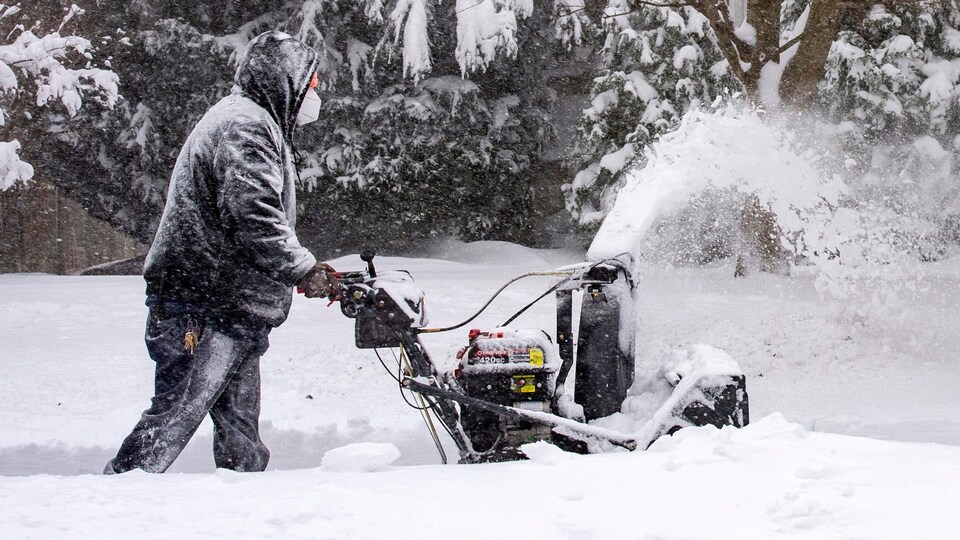 Un homme passe la souffleuse après une tempête de neige en périphérie de Boston le 17 décembre 2020.