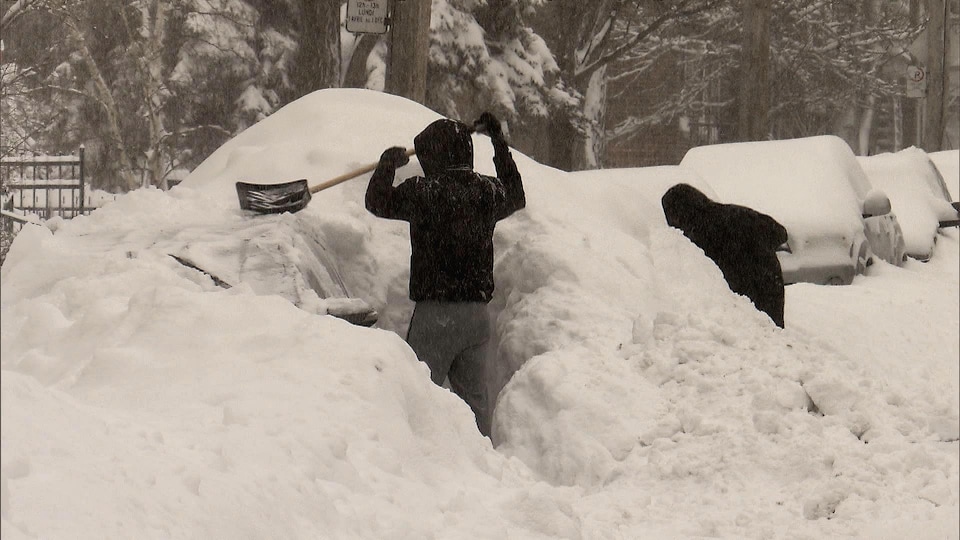 Un automobiliste tente de retrouver sa voiture sous la neige.