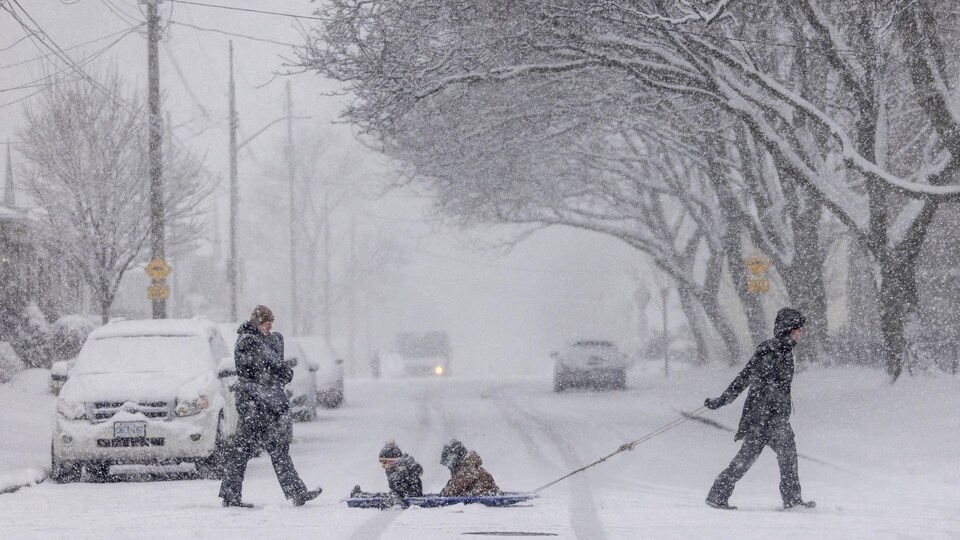 Une famille ontarienne traverse la rue alors que la neige tombe fortement, le 25 janvier 2023, à Hamilton. 