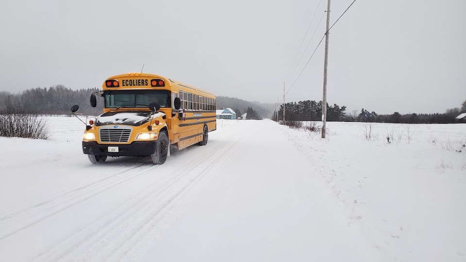 Un autobus scolaire file sur une route de campagne enneigée, à Saint-Donat.