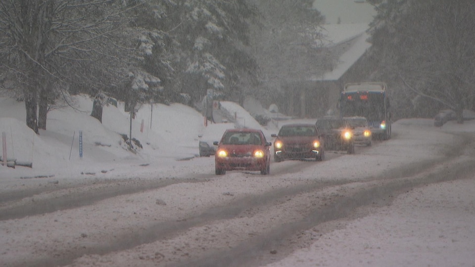 Des véhicules circulent sous la neige.