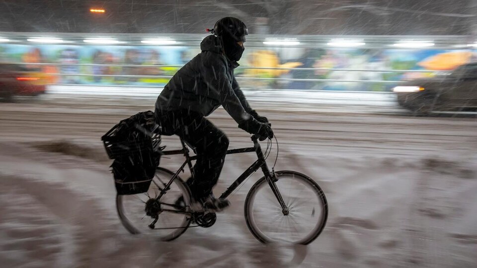 Un homme à vélo dans la neige à Toronto.