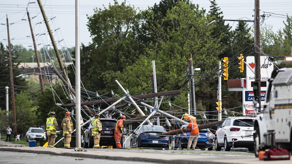 Des pompiers et des travailleurs des services publics constate les dégâts après le passage d'une tempête, à Ottawa. 