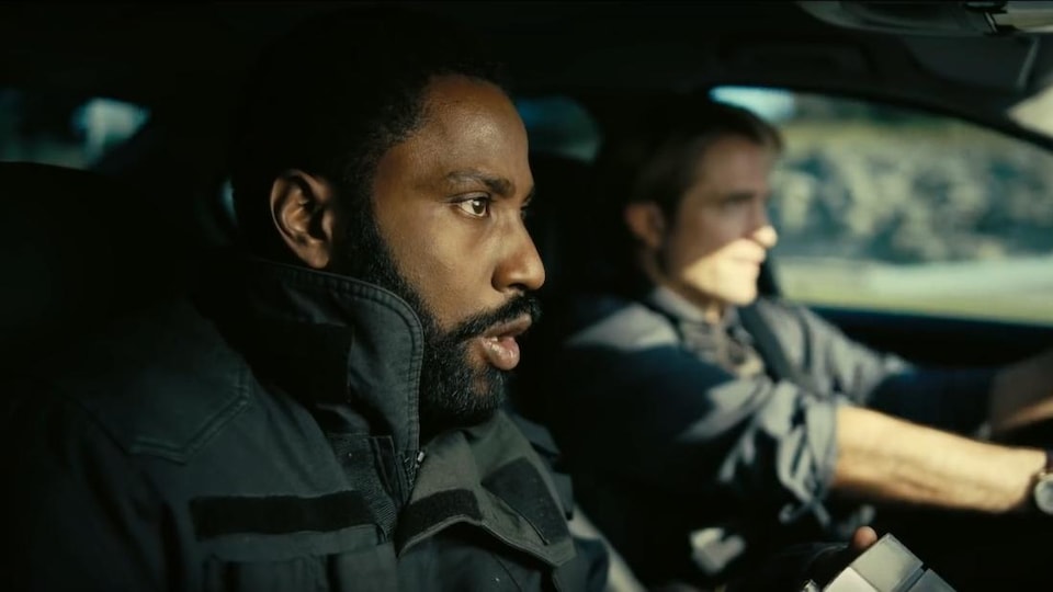 John David Washington et Robert Pattinson sont à l'avant d'une voiture.